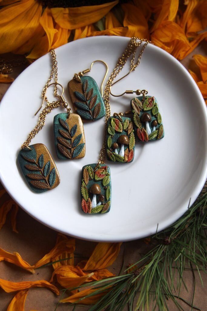 Autumn earrings and leaf pendants from polymer clay. One of the fall jewelry sets contains colorful branches with autumn leaves. The mushroom jewelry set has tiny brown fungi and colorful leaves.